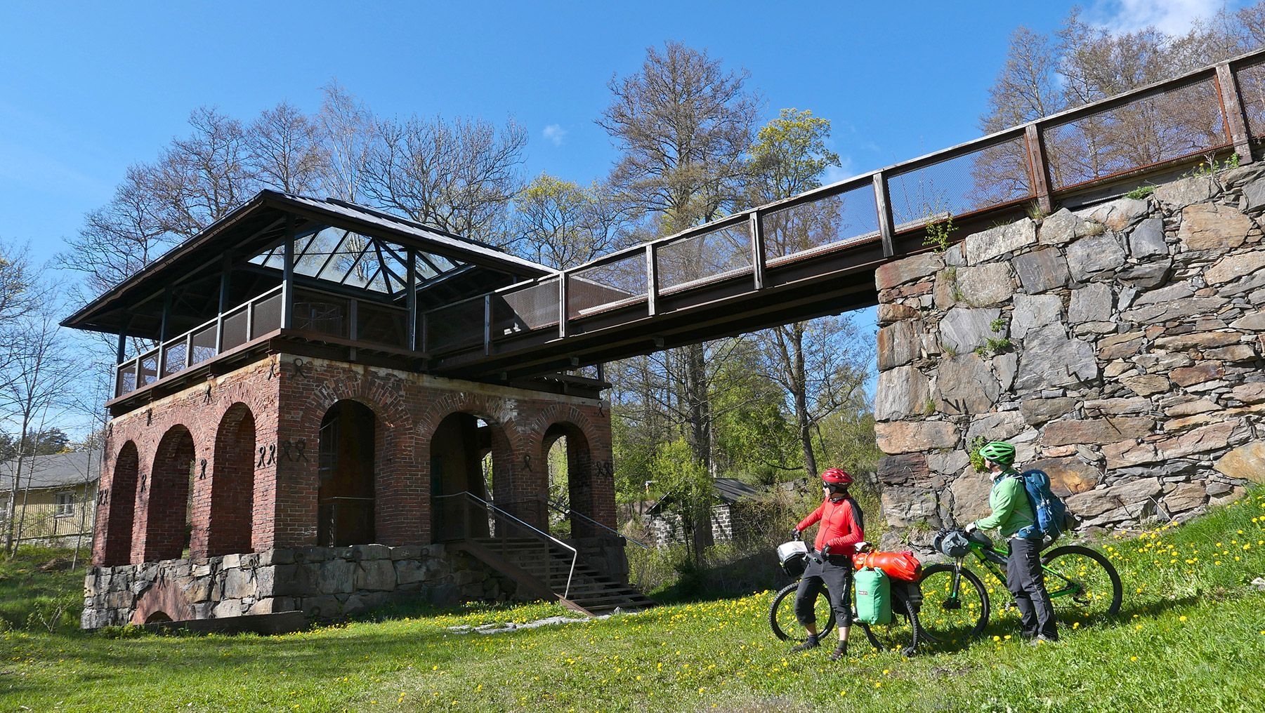 Two cyclists look at an old building, while travelling through Kimitoön.