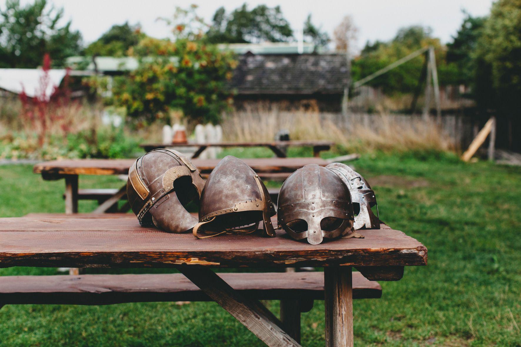 A collection of Viking helmets on a wooden table at the Rosala Viking Centre.