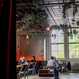 Plants hang from the ceiling at Logomo's restaurant, where diners are enjoying a meal.