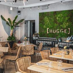 The natural-looking interior of Hugge, complete with wicker furniture and green plants.