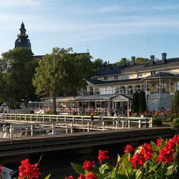 The exterior of Naantalin Kaivohuone, surrounded by red flowers and situated beside the harbor.