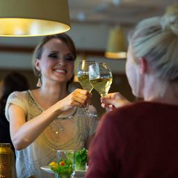 Two women raise their glasses of wine together in a toast at Naantali Spa Hotel and Resort.