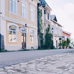 A cobblestone street in Naantali's Old Town, lined with pastel-coloured wooden buildings.