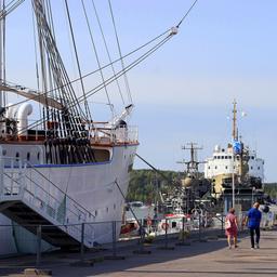 Visitors stroll beside Forum Marinum's museum ships, which are moored to the banks of the Aura River.